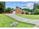 View of a sloped driveway leading to a brick home with an attached garage, set among lush greenery at 124 Crown Walk, Mcdonough, GA 30253