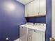 Modern laundry room featuring white washer and dryer and white storage cabinets against blue wall at 2624 Chase Rdg, Kennesaw, GA 30144