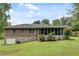 View of the brick house with garage and enclosed sunroom surrounded by lush greenery on a sprawling lawn at 2653 Elkhart Sw Cir, Marietta, GA 30064