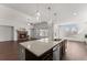 Open-concept kitchen with island, seamlessly flowing into the living room with a stone fireplace and large windows at 7995 Brewton Creek Dr, Cumming, GA 30028