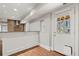 Basement kitchen area with wood flooring, stainless hood, white cabinetry and access door at 1131 Mayfield Dr, Decatur, GA 30033