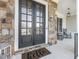 Elegant stone entryway with double doors and rocking chairs on the porch at 1963 Skybrooke Ln, Hoschton, GA 30548