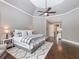 Bright main bedroom featuring a tray ceiling, ceiling fan, and plush carpet with seating area near the large windows at 1963 Skybrooke Ln, Hoschton, GA 30548