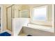 Relaxing bathtub with a tiled surround, a separate glass shower, and a frosted window for privacy at 1059 Verbena Way, Auburn, GA 30011
