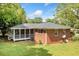 A view of the home's backyard featuring a screened-in porch, grassy area, and brick exterior at 2078 Olive Springs Se Rd, Marietta, GA 30060