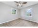 Bright bedroom with wood-look floors, ceiling fan, and two windows offering outdoor views at 2078 Olive Springs Se Rd, Marietta, GA 30060