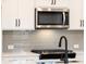 Close up on kitchen with modern appliances, grey subway tile backsplash, and white cabinetry at 4523 Moray Dr, Mableton, GA 30126