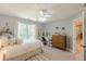 A bright bedroom featuring a queen bed, ceiling fan, window, and dresser at 830 Hightower Trl, Oxford, GA 30054