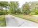 Spacious driveway leading to a home, surrounded by lush greenery and tall trees at 830 Hightower Trl, Oxford, GA 30054