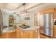 Kitchen island with cooktop, stainless steel refrigerator, wood cabinets, and dining area at 830 Hightower Trl, Oxford, GA 30054