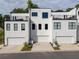 Modern townhomes featuring white exteriors, black trim, and private garages, set against a backdrop of lush trees at 2150 Tidwell Ln # 5, Atlanta, GA 30318