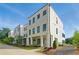 Modern townhome with a white painted brick exterior and black framed windows, complemented by lush landscaping and a blue sky at 2150 Tidwell Ln # 5, Atlanta, GA 30318