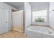 Bright bathroom featuring a large soaking tub, a walk-in shower, and warm neutral tile at 3134 Milloak Ct, Buford, GA 30519