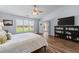 Bright bedroom featuring wood floors, ceiling fan, a large window, and a TV with built in storage at 3134 Milloak Ct, Buford, GA 30519