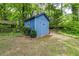 Charming blue shed in a backyard, perfect for storage or a hobby space, surrounded by lush greenery and mature trees at 3739 Lake Carlton Rd, Loganville, GA 30052