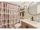 Well-lit bathroom with a vanity, round mirror, decorative shower curtain, and tiled flooring at 1359 Cedar Park Pl, Stone Mountain, GA 30083