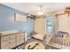 Bedroom with baby furniture, overhead ceiling fan, and a blue accent wall at 1359 Cedar Park Pl, Stone Mountain, GA 30083