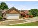 Brick home featuring a two car garage, covered patio and mature trees at 5917 Southland Dr, Stone Mountain, GA 30087