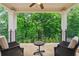 An outdoor stone tiled balcony with two chairs and wrought iron railing overlooking a lush green backyard at 8109 Lawnview, Alpharetta, GA 30022