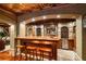 Elegant home bar featuring a copper ceiling, stone accents, wood cabinetry, and stools creating an inviting space for entertaining at 8109 Lawnview, Alpharetta, GA 30022
