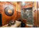 Rustic bathroom featuring a stone shower, copper sink, unique mirror, and wood accents, creating a warm and inviting space at 8109 Lawnview, Alpharetta, GA 30022