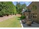A backyard featuring a well-maintained lawn, mature trees, retaining wall, and patio with comfortable seating at 8745 Islesworth Ct, Duluth, GA 30097