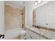 Bathroom featuring a granite vanity top, soaking tub with tile surround, and modern fixtures at 8745 Islesworth Ct, Duluth, GA 30097