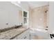 Bathroom featuring a granite vanity top, soaking tub with tile surround, and modern fixtures at 8745 Islesworth Ct, Duluth, GA 30097
