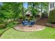 Stone patio in backyard featuring outdoor seating, surrounded by lush greenery and mature trees at 9115 Nesbit Lakes Dr, Alpharetta, GA 30022