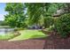 Backyard with a stone patio and blue outdoor seating next to a lake, surrounded by lush landscaping at 9115 Nesbit Lakes Dr, Alpharetta, GA 30022