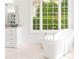 Bright bathroom featuring a modern soaking tub, large window with lush greenery views at 9115 Nesbit Lakes Dr, Alpharetta, GA 30022