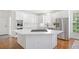 Modern kitchen showcasing white cabinets, stainless steel appliances, and a stylish island cooktop and hardwood floors at 9115 Nesbit Lakes Dr, Alpharetta, GA 30022