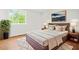 Comfortable bedroom featuring a large bed, decorative pillows, hardwood floors, and a bright window at 1355 Tucker Woods Dr, Norcross, GA 30093