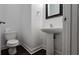 Half bathroom featuring a pedestal sink, toilet, modern mirror, and dark wood-like flooring at 2275 Copper Trail Ln, Buford, GA 30519