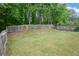 Expansive backyard featuring a lush lawn, framed by a wooden fence, and mature trees for privacy at 3381 Grovewood Ln, Duluth, GA 30096