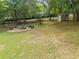 Expansive backyard with mature trees features a fire pit with stone pavers and adirondack chairs at 3642 River Club Dr, Cumming, GA 30041