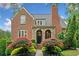 Charming brick home with a stone arched entryway and lush, colorful landscaping at 3642 River Club Dr, Cumming, GA 30041