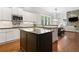 Bright kitchen with white cabinets, black countertops, a dark-wood island, and hardwood floors, open to the living room at 3642 River Club Dr, Cumming, GA 30041