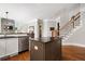 Well-lit kitchen featuring a dark-wood island, stainless steel appliances, and hardwood floors, open to the staircase at 3642 River Club Dr, Cumming, GA 30041