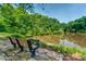 A serene view from a bench overlooking the pond, surrounded by lush greenery at 3642 River Club Dr, Cumming, GA 30041