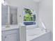 Bright bathroom featuring a soaking tub with window views, vanity, and white cabinets at 1965 Tiner Ct, Cumming, GA 30041