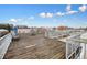 Spacious rooftop deck with weathered wood, a metal railing, and a view of nearby buildings under a bright, cloudy sky at 890 Memorial Se Dr # 102, Atlanta, GA 30316