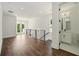 Hallway with wood floors, metal railing, leading to glass paneled doors and an open bathroom at 2200 Carlton Ct # 6, Atlanta, GA 30318