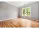 Cozy bedroom with neutral walls, bright window, light-colored hardwood floors, and ample natural light at 7035 Hampton Bluff Way, Roswell, GA 30075