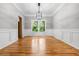 Elegant dining room featuring hardwood floors, wainscoting, modern lighting, and large windows offering bright light at 7035 Hampton Bluff Way, Roswell, GA 30075