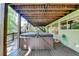 Back deck with a hot tub and wooden beamed roof surrounded by a lush green forest at 975 Timber Lake Trl, Cumming, GA 30041