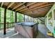 Back deck with a hot tub and wooden beamed roof surrounded by a lush green forest at 975 Timber Lake Trl, Cumming, GA 30041