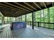 Back deck with a hot tub and wooden beamed roof surrounded by a lush green forest at 975 Timber Lake Trl, Cumming, GA 30041