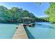 Lake view of a wooden dock with a covered sundeck in a wooded area under a bright blue sky at 975 Timber Lake Trl, Cumming, GA 30041