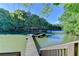 Wooden dock on the water surrounded by lush trees under a sunny sky, offering a serene waterfront experience at 975 Timber Lake Trl, Cumming, GA 30041